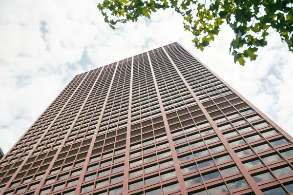 Tall residential high-rise building with grid pattern windows against cloudy sky