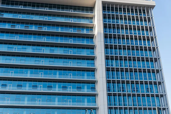 Modern high-rise building exterior with reflective blue glass windows and metal framing