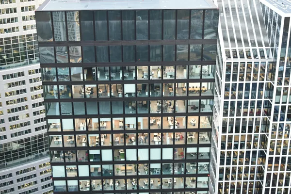 Modern office building facade with numerous reflective glass windows and dark frames