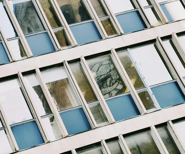 Dirty apartment building facade with blue-tinted windows needing professional cleaning