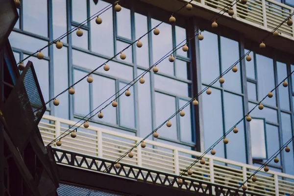 Modern building facade with large windows and decorative hanging brass spheres