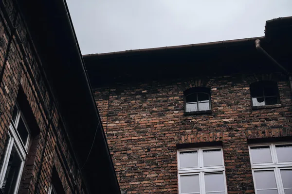 Brick building exterior with white-framed windows and metal roof detail