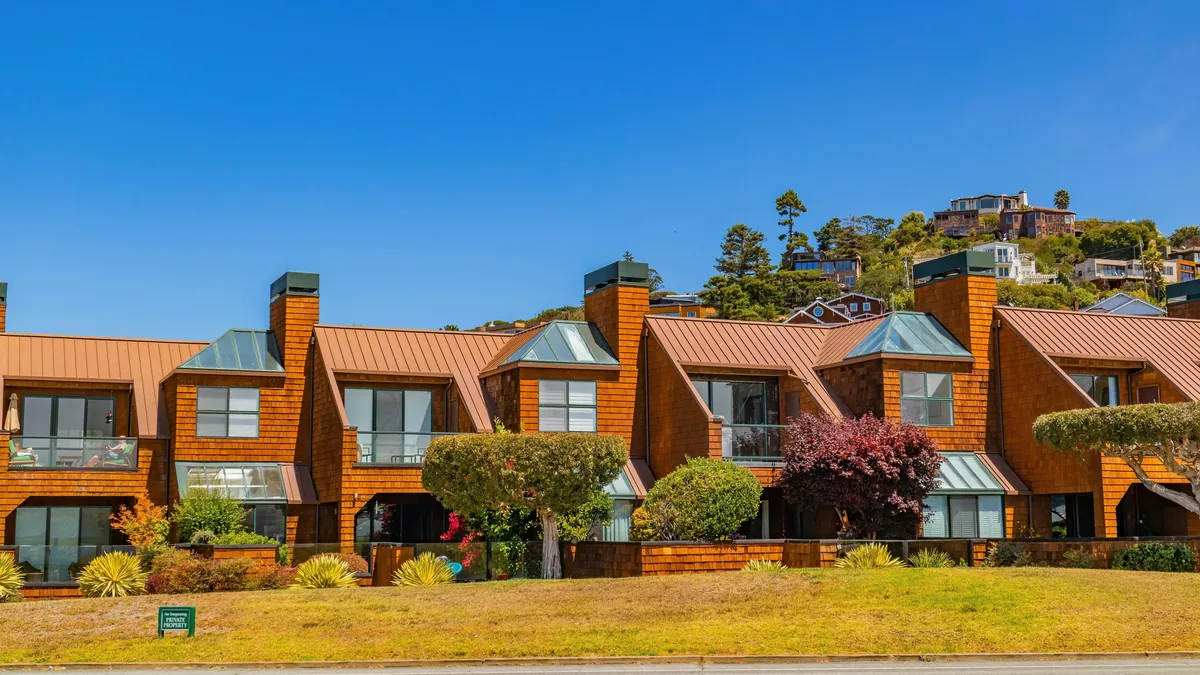 Modern residential townhouses with copper roofing and large windows on hillside