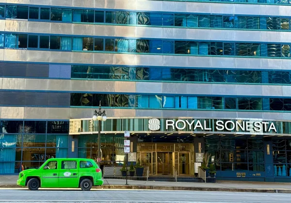 Modern glass and stone building facade with reflective windows and green taxi