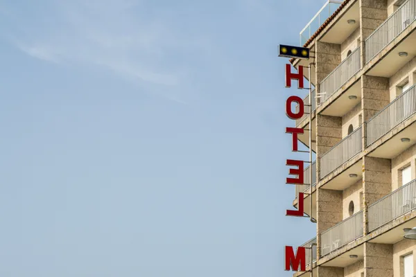 Vertical hotel sign on multi-story building facade with balconies