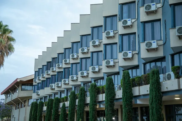 Modern stepped building facade with multiple air conditioning units and windows