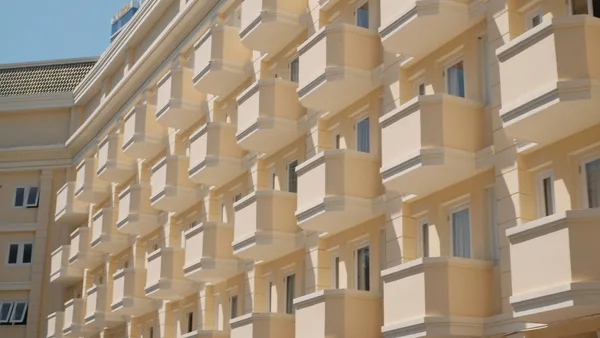 Modern residential building facade with numerous windows and curved balconies