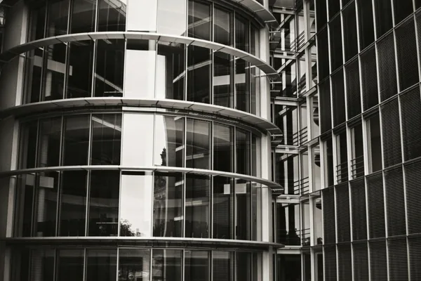 Modern curved glass building exterior with multiple reflective windows and metal frames