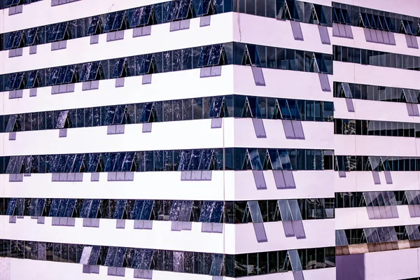 Modern striped building facade with reflective glass windows and solar panels