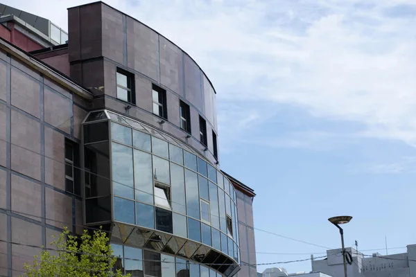 Modern office building exterior with large curved glass windows and dark facade