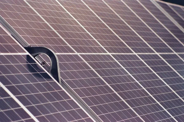 Metal mounting bracket installed on solar panel array in sunlight